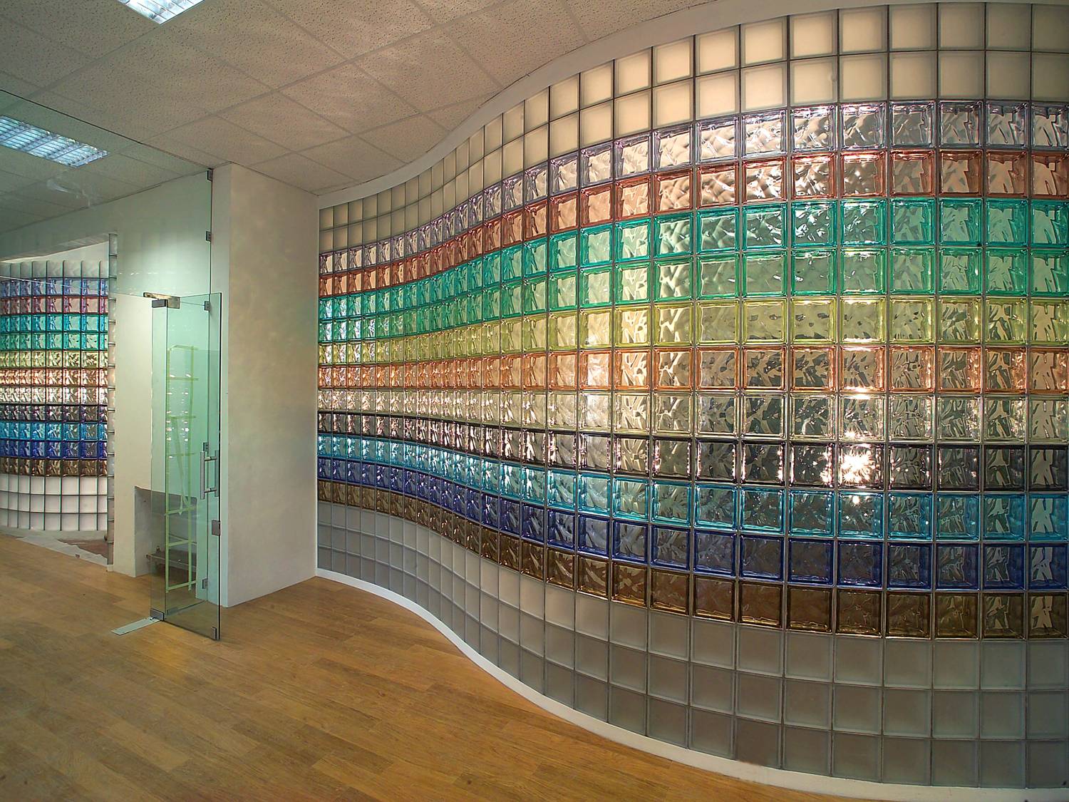 Curved interior wall built from bands of coloured glass blocks